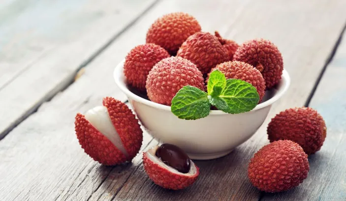 Lychees in a bowl on a wooden board