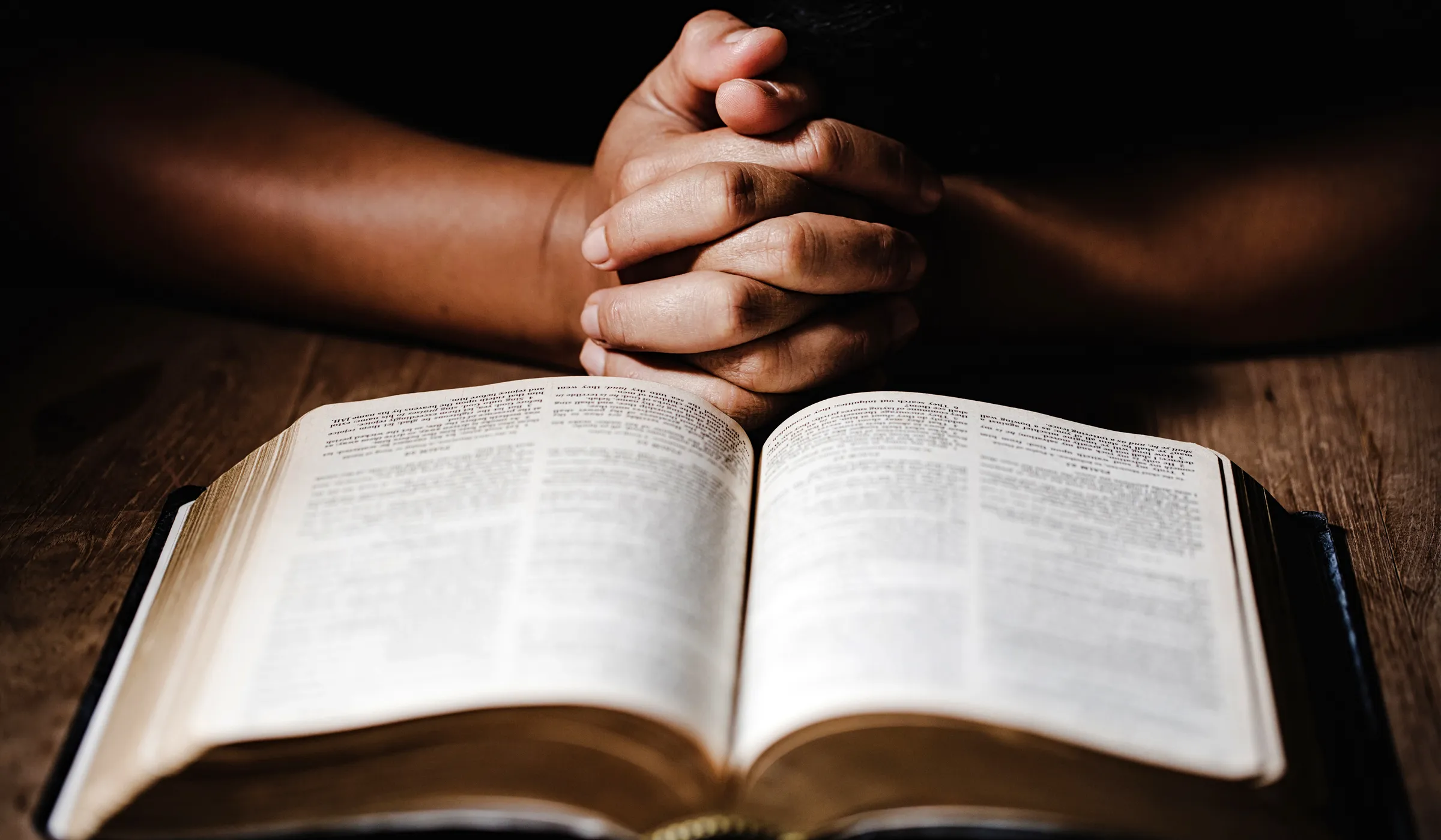 Mains avec doigts croisés au-dessus d'une bible